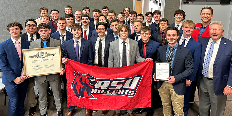 large group of men in suits with RSU Hillcat flag