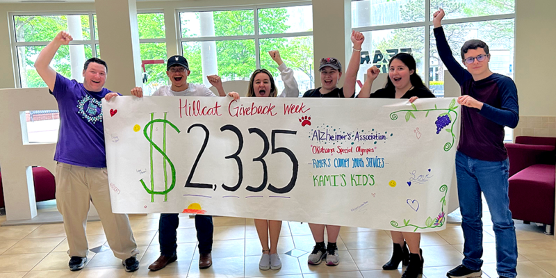 students holding banner with dollar amount they raised