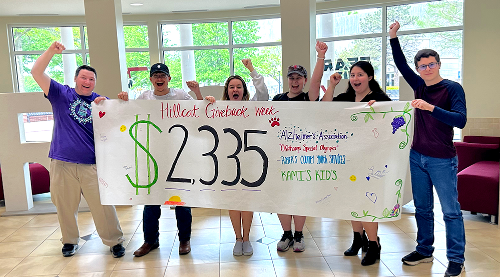 students holding banner with dollar amount they raised