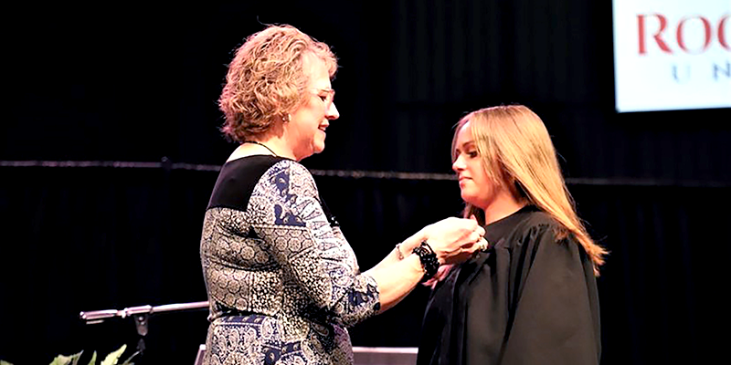 woman putting a pin on graduate