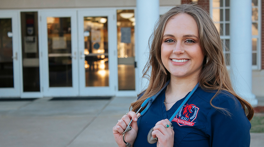 nursing student in scrubs holding stethoscope