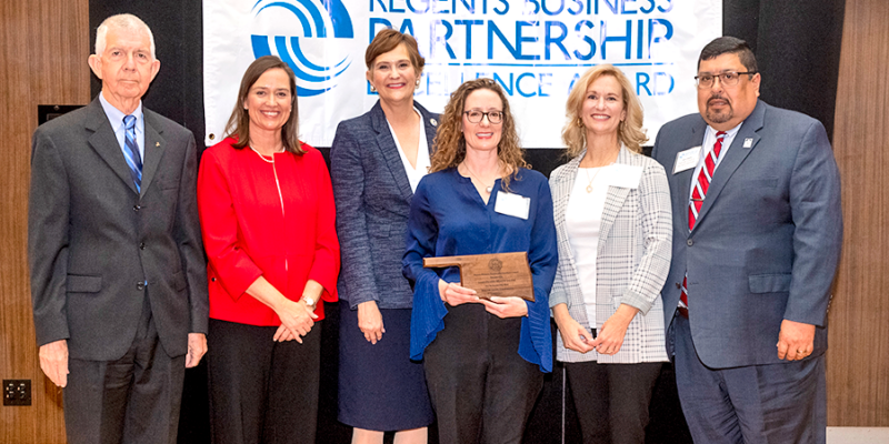 group of people posing for photo with award