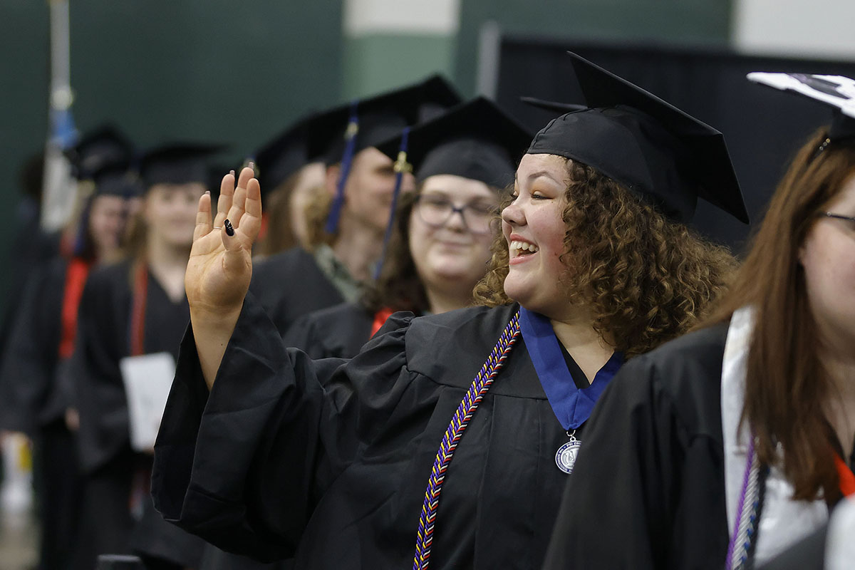 girl smiling and waving from graduation