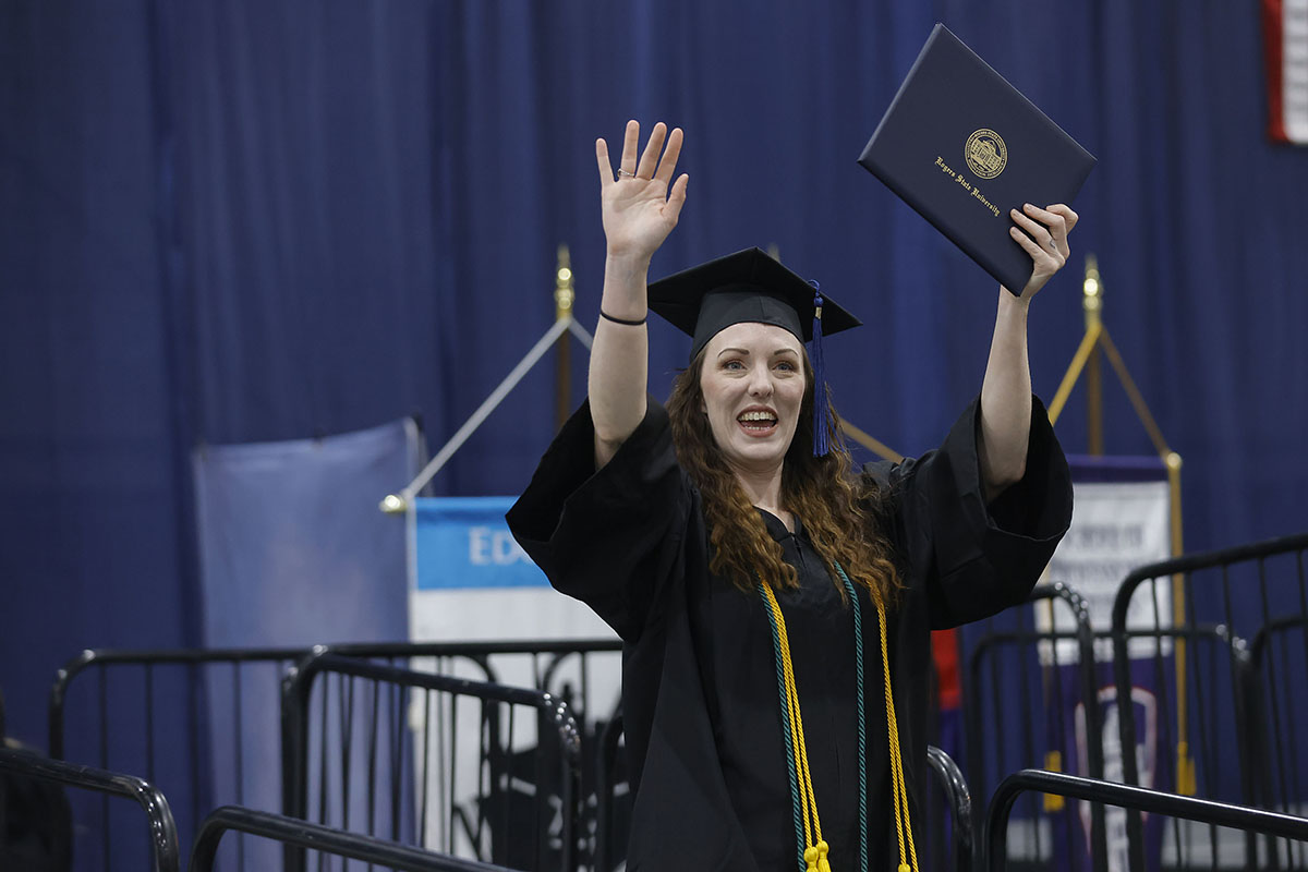 woman holding up diploma and waving