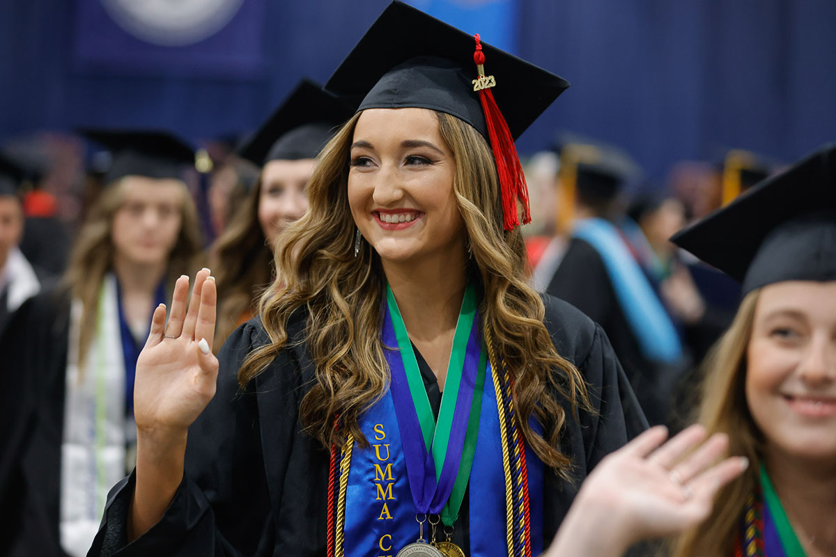 girl waving from graduation ceremony