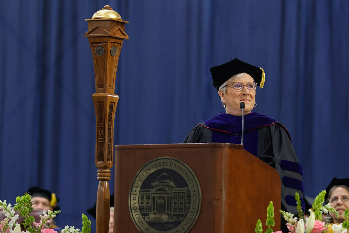woman in cap and gown speaking at podium