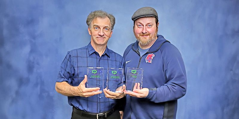 two men holding trophies