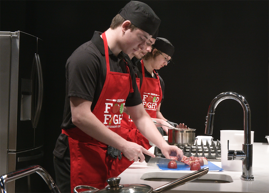 boys wearing aprons and cooking in a food competition