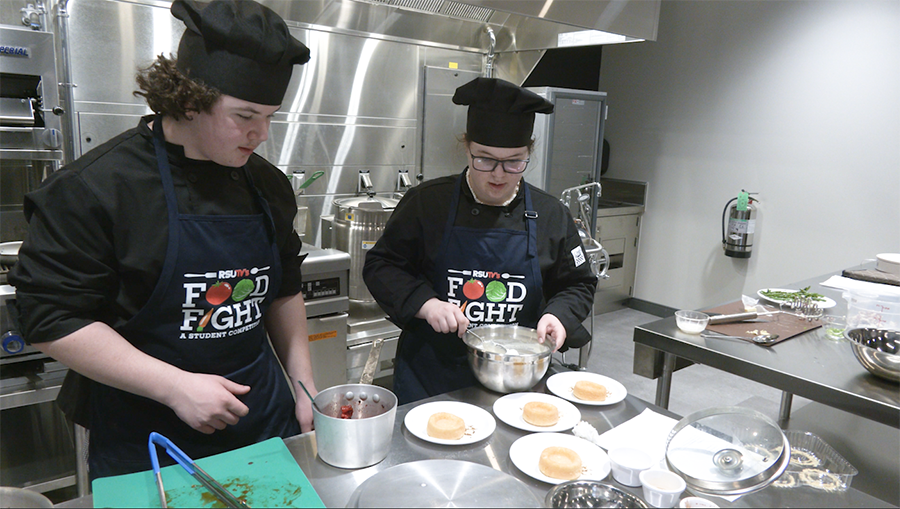 boys wearing aprons and cooking in a food competition