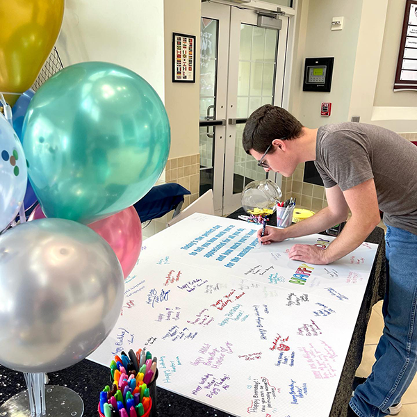 boy signing oversized birthday card