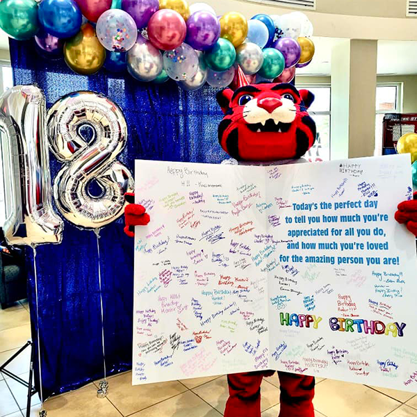 cat mascot holding oversized birthday card