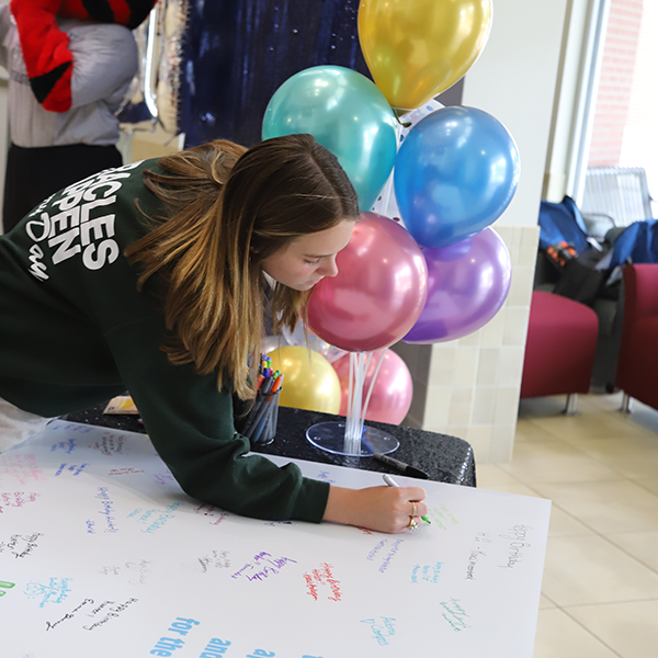 girl signing oversized birthday card