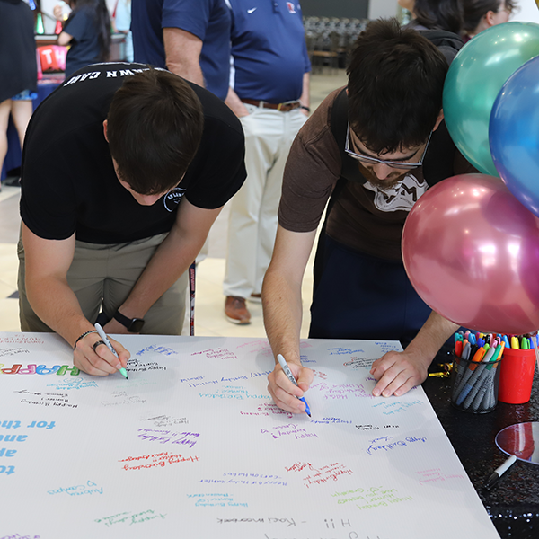 2 boys signing oversized birthday card