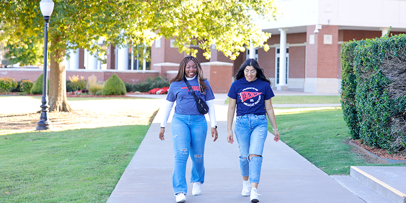 2 girls walking across campus