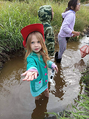 girl holding worm from water