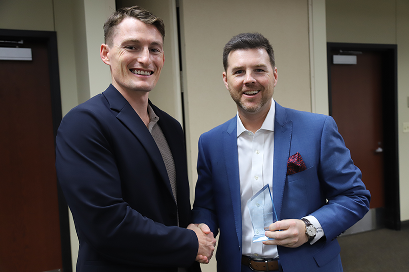 two men shaking hands with award