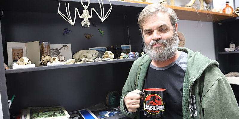Dr. Chris Shelton standing by shelves of animal bones