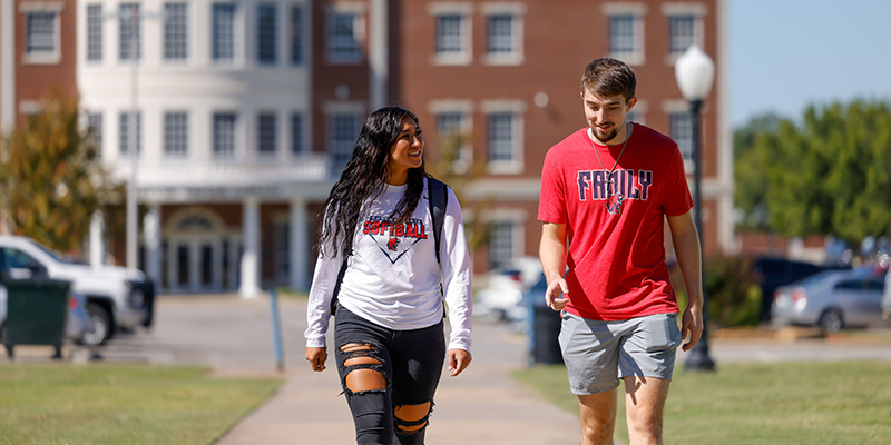 Girl and boy walking in front of library