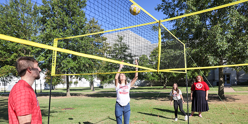 students playing 4 square volleyball on college campus