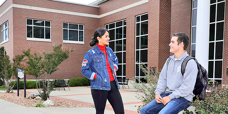 Girl and boy talking outside on campus.