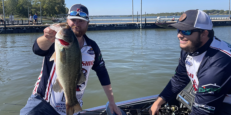 two men on boat holding a fish they caught