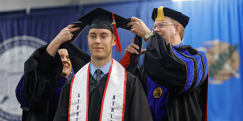 Male graduate receiving masters hooding.