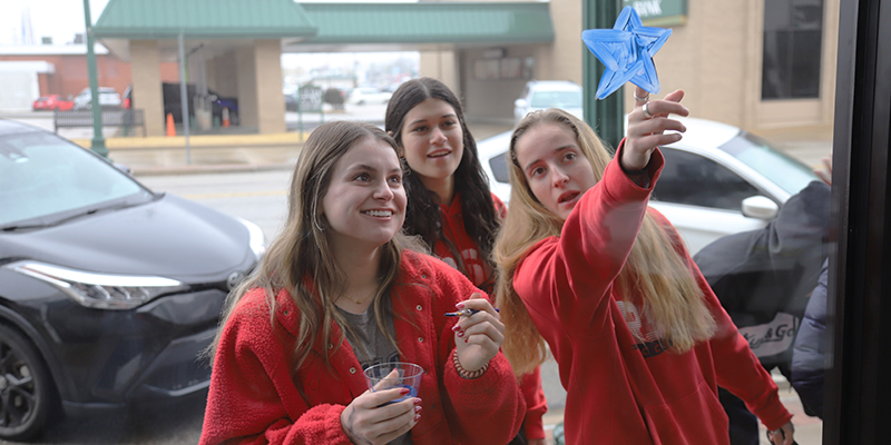 Students painting windows of business for homecoming.