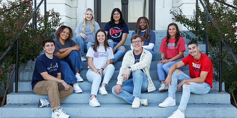 group of students sitting on steps outside building