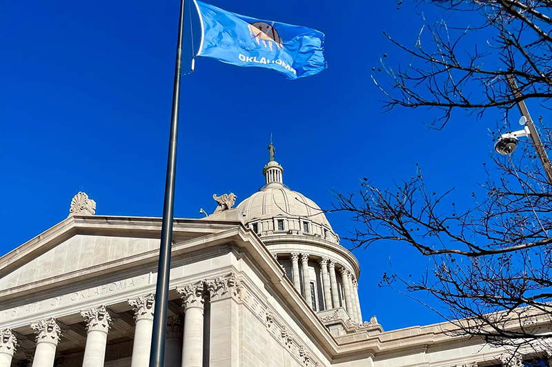 capitol building with dome and oklahoma flag flying