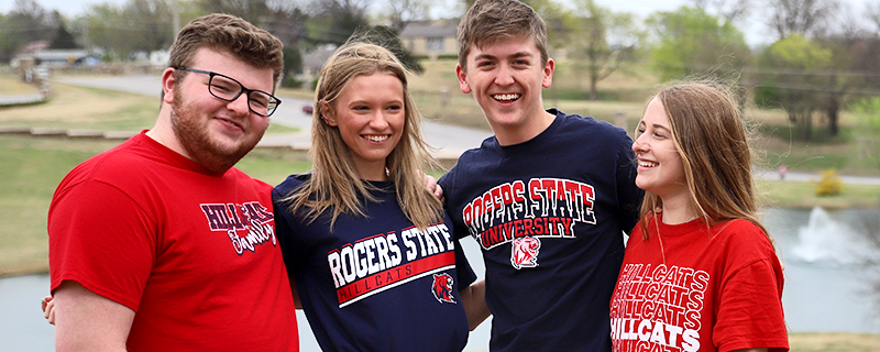 Students laughing and talking in front of lake on campus.