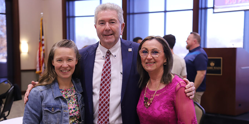 Man in suit with two women posing for photo