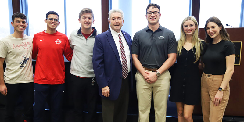 Man in college students posing for photo