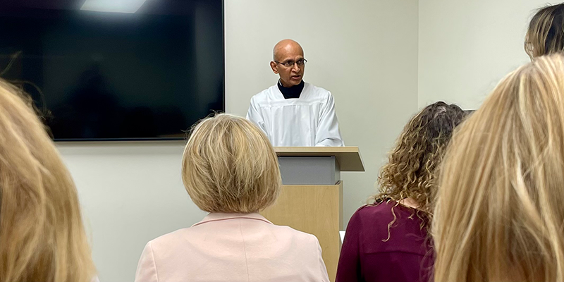 man in white robe speaking to group