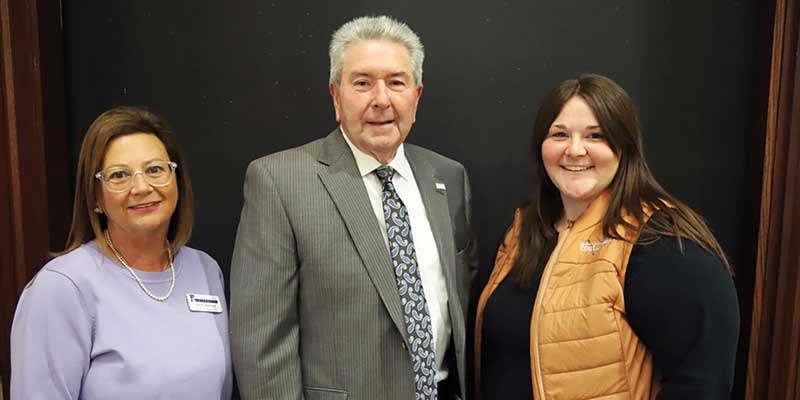 Man and two women standing for photograph.