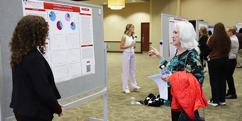 Students presenting their capstone projects with poster boards.