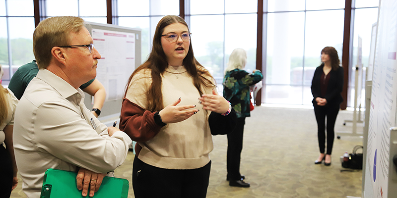 Students presenting their capstone projects with poster boards.