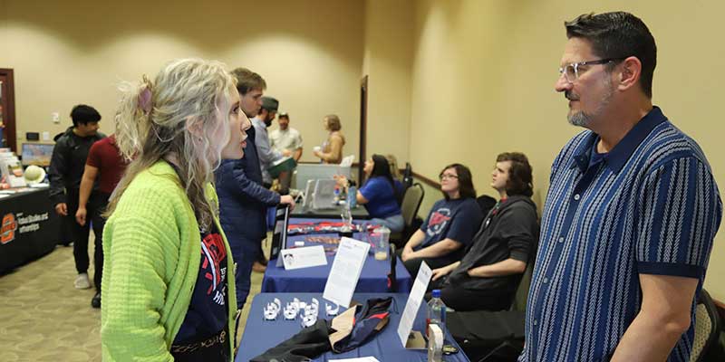 Man talking to woman at a career fair.