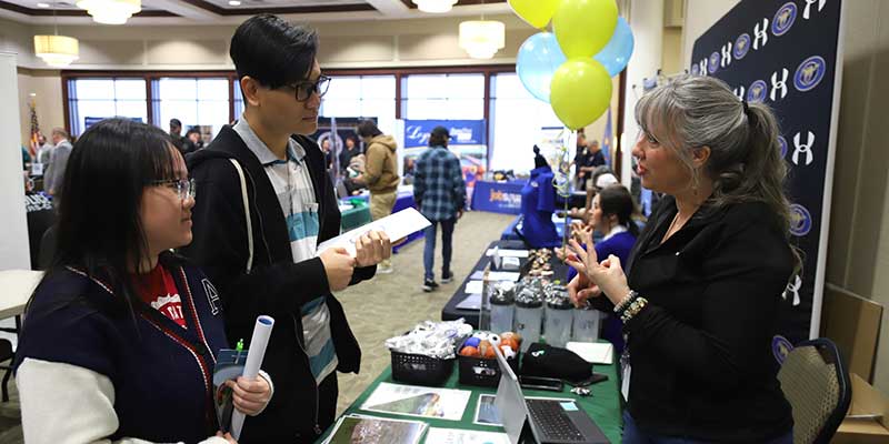 Woman talking to students at a career fair.