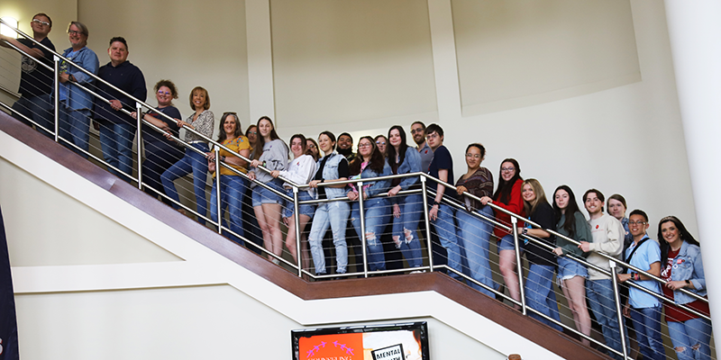 Large group of people lined up on stairs all wearing denim.