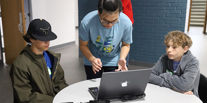 Instructor helping students on laptop.
