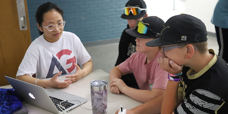 Instructor helping students on laptop.