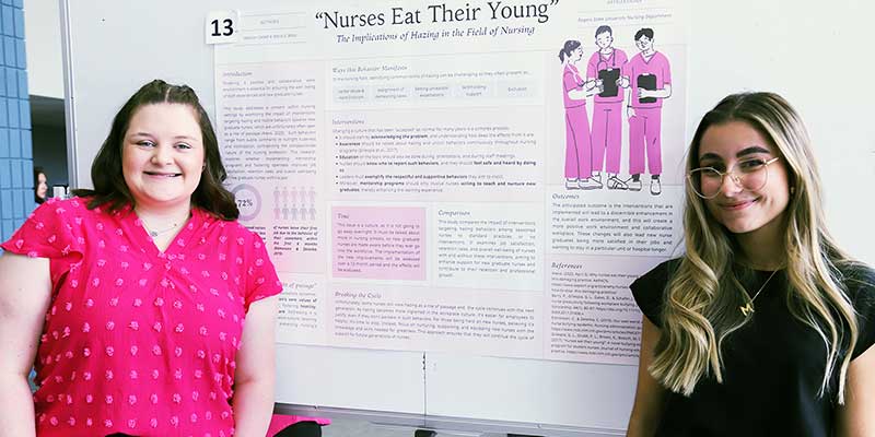 Two girls standing by a poster presentation.