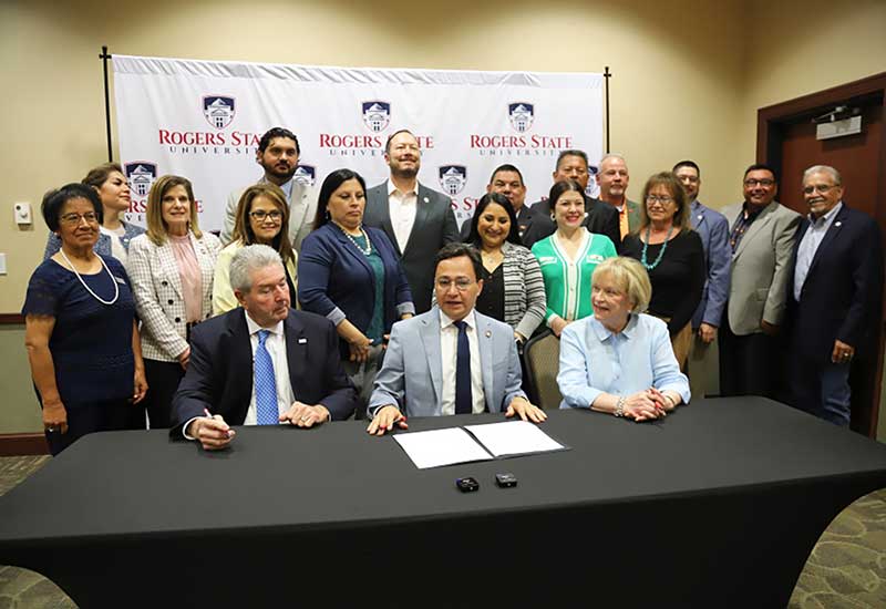 Group photo with 3 sitting at table and others standing behind.