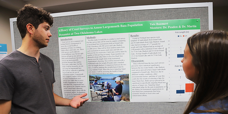 A male students presents his research poster.