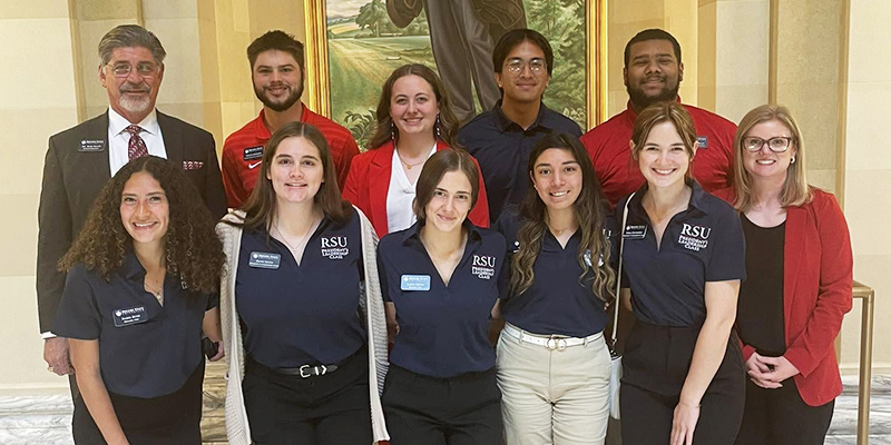 A group of students and employees pose at the state Capitol