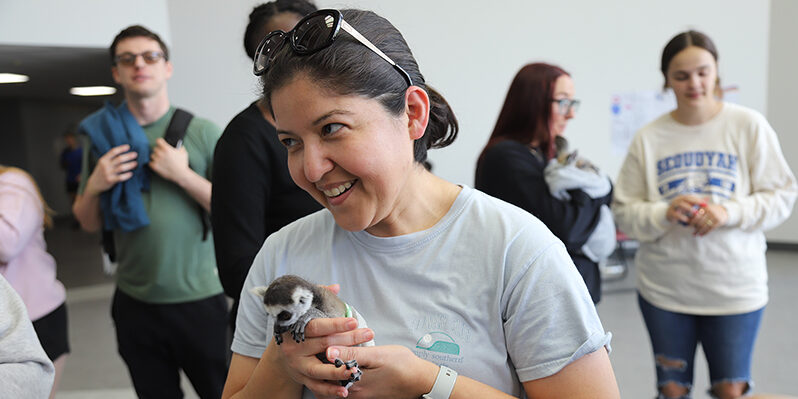 A smiling woman holds a small lemur
