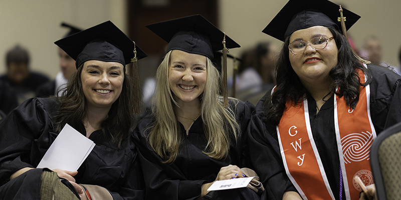 Three smiling graduates pose for the camera