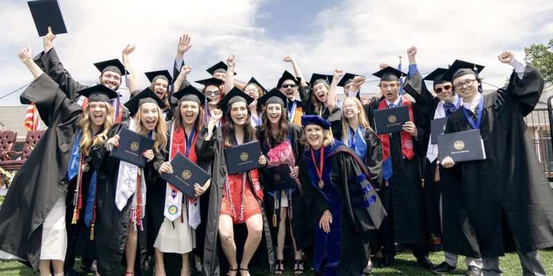 A large group of graduates celebrates together with professors