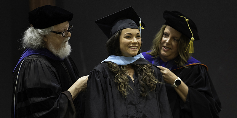 A master's degree graduate received her hood from two professors.