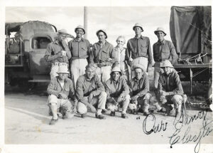 Military unit standing together in two lines with vehicles